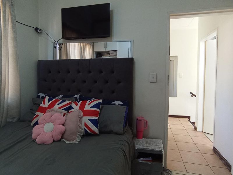 A bedroom featuring tiled flooring and a built-in mirror, with direct access to the hallway.