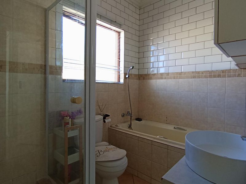 A functional bathroom featuring a shower enclosure, bathtub, toilet, and a modern vessel sink with subway tile wall finishes.