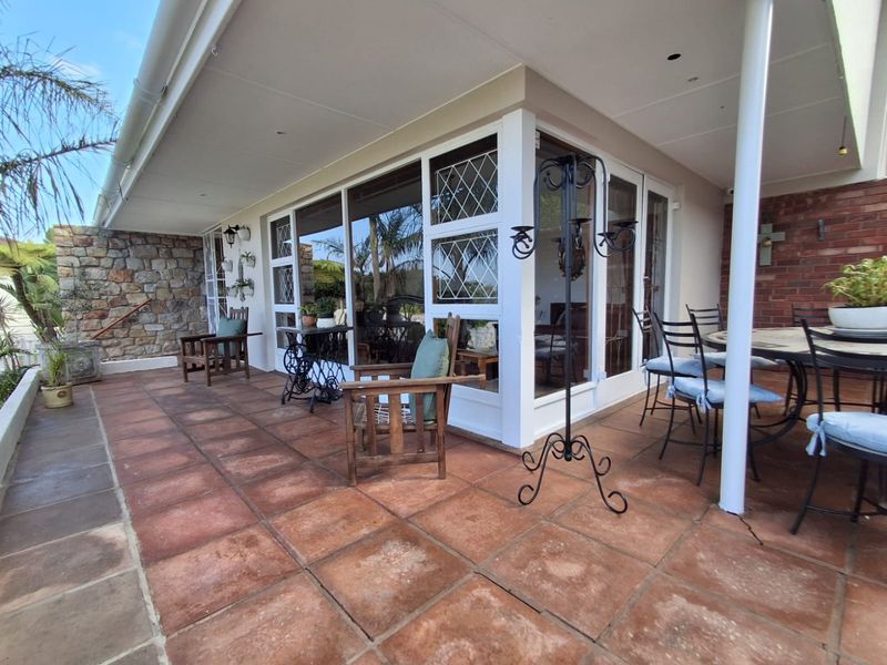 A spacious covered patio featuring terracotta tiling, stone and brick wall accents, and large sliding glass doors providing access to the interior.