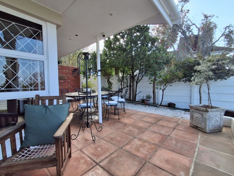 A covered outdoor patio featuring terracotta tiling, recessed lighting, and a secure boundary wall, providing a pleasant space for outdoor dining and relaxation.