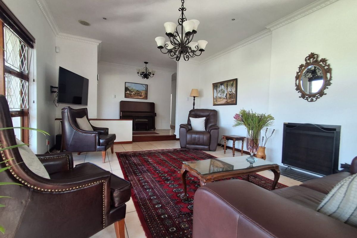 Spacious living room featuring a fireplace, tiled flooring, crown molding, and elegant chandeliers, creating a comfortable and inviting atmosphere.