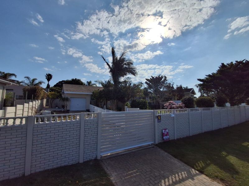 Front view of the property featuring a secure brick boundary wall, gated entrance, paved driveway, and a single garage.