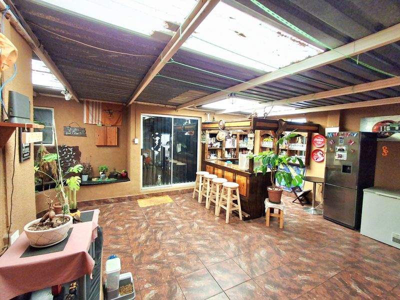 Covered outdoor patio area featuring a built-in bar, tiled flooring, and translucent roof panels providing natural light.
