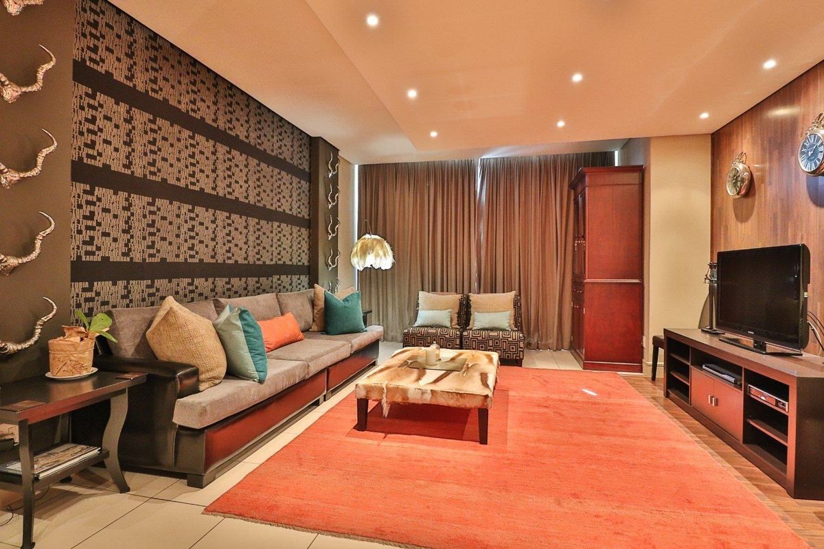 A well-maintained living room featuring recessed downlighting, tiled flooring, and decorative wood paneling, creating a warm and inviting atmosphere.