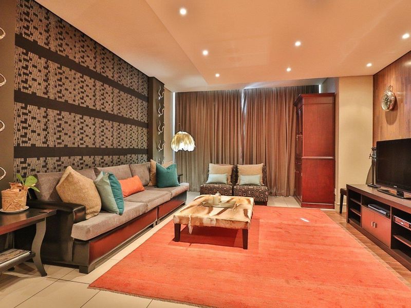 A well-maintained living room featuring recessed downlighting, tiled flooring, and decorative wood paneling, creating a warm and inviting atmosphere.