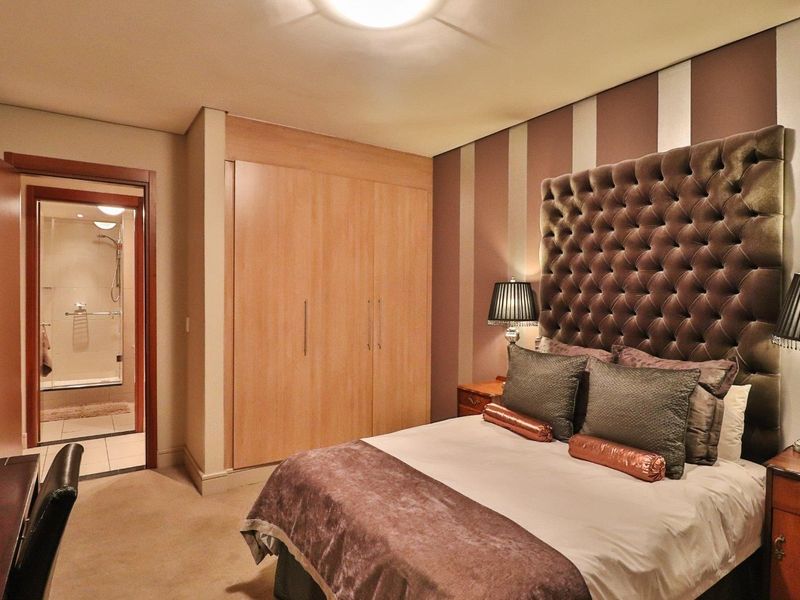 A well-maintained bedroom featuring a built-in wardrobe, plush carpeting, and direct access to an en-suite bathroom with a shower.