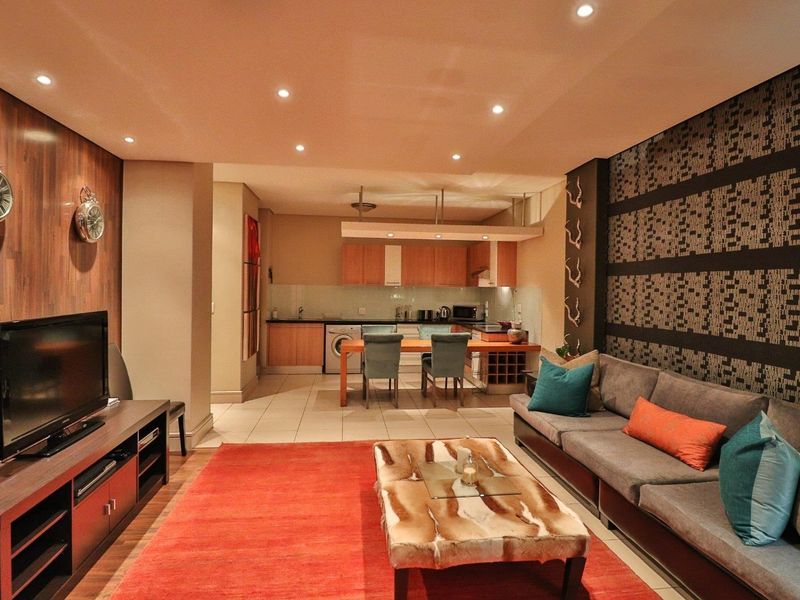 Open-plan living and kitchen area featuring a combination of wood laminate and tiled flooring, recessed lighting, and modern built-in cabinetry.