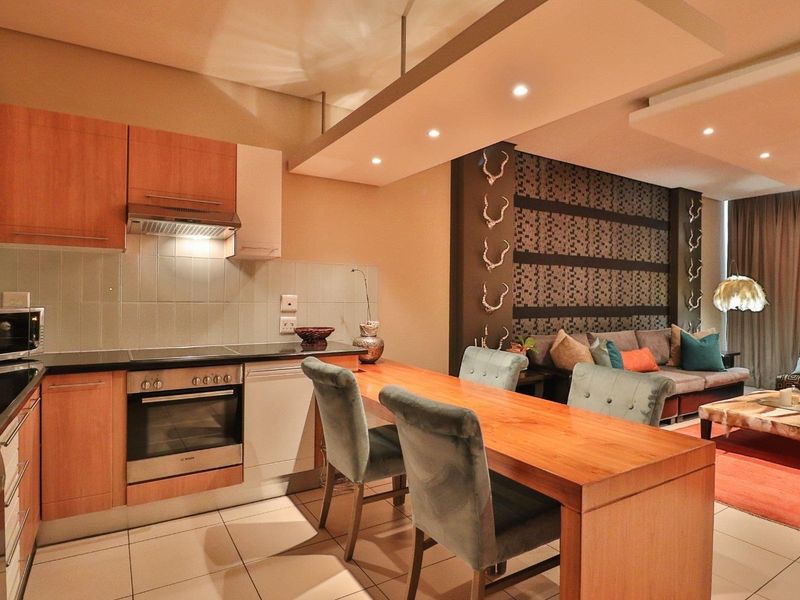 Open-plan living area featuring a modern kitchen with wood-finish cabinetry, integrated appliances, and a breakfast bar flowing into a comfortable lounge space.