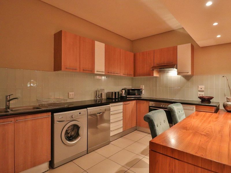 A functional kitchen featuring wood-finish cabinetry, granite countertops, a tiled backsplash, and integrated appliances including an oven and extractor fan.