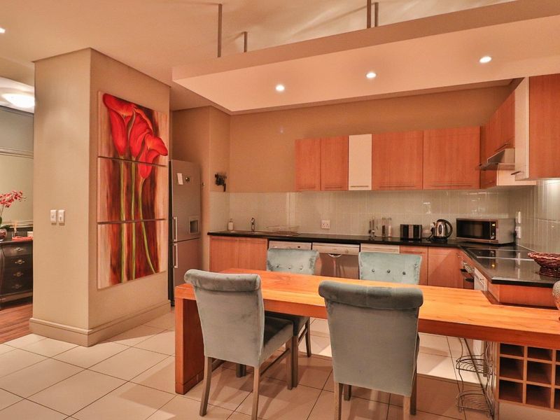 A functional kitchen featuring wood-finish cabinetry, stone countertops, integrated appliances, and a breakfast bar, illuminated by recessed ceiling lighting.