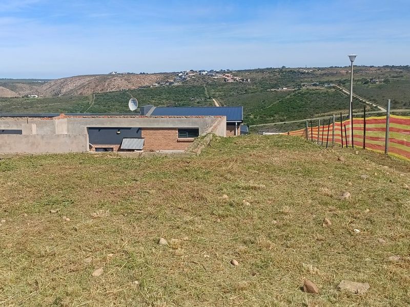 A view of the vacant residential land plot featuring natural grass terrain and perimeter fencing with surrounding landscape views.