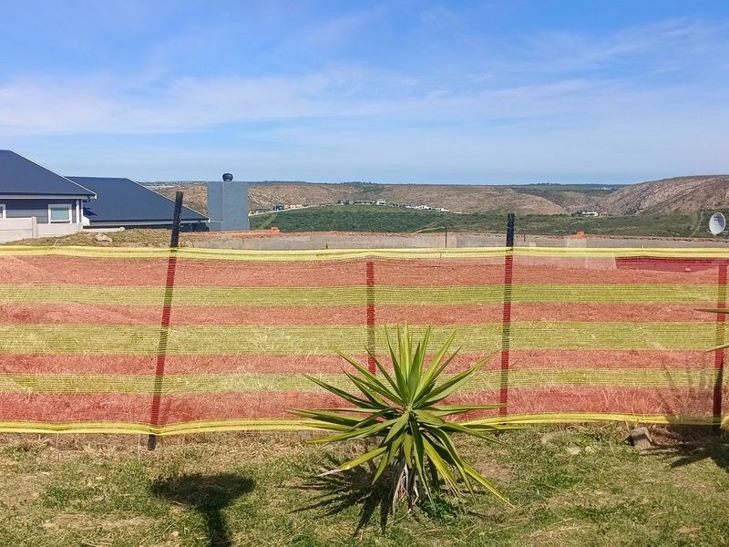 A vacant residential plot featuring a concrete foundation and construction fencing, offering expansive views of the surrounding landscape.