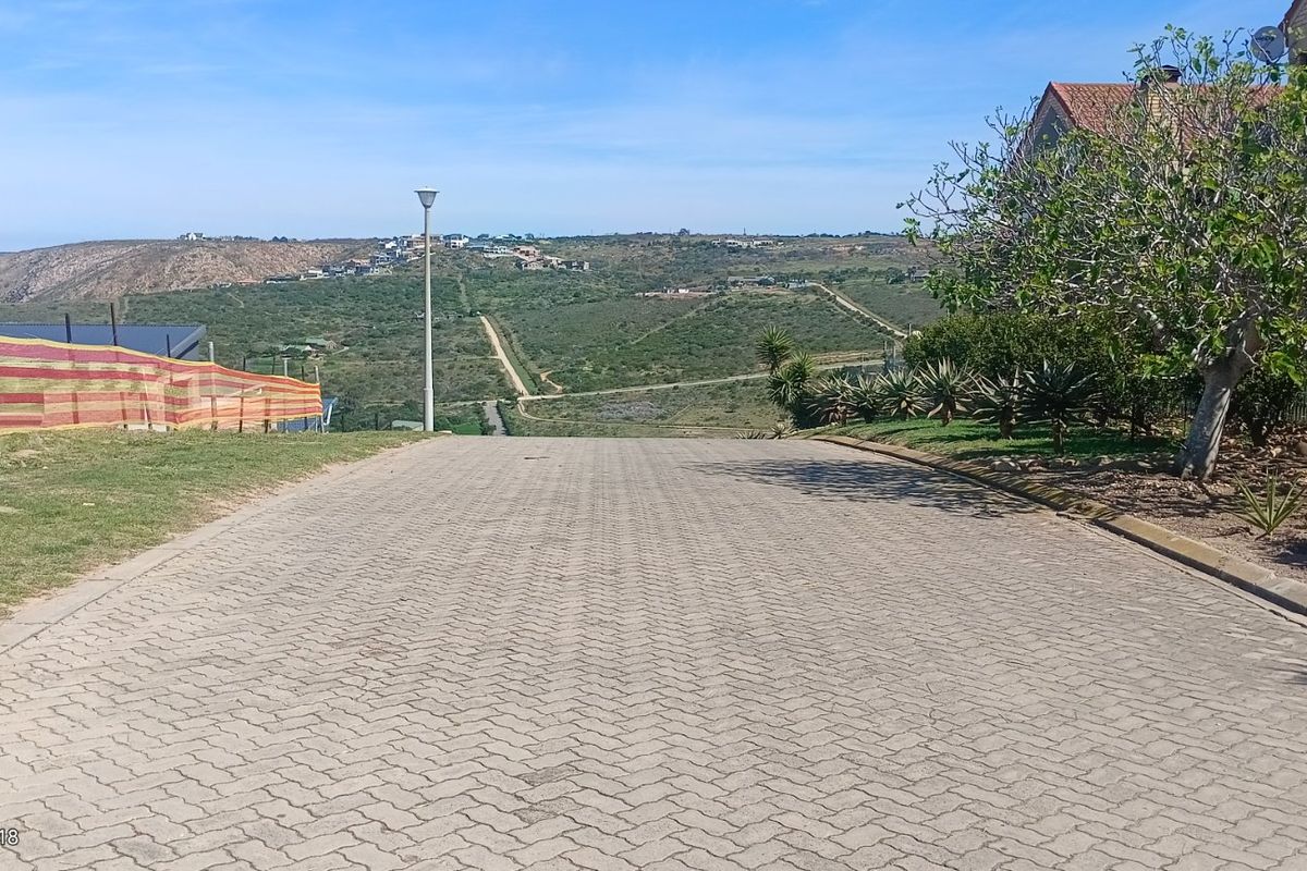 A view looking down a paved residential street with surrounding landscape and neighborhood views.