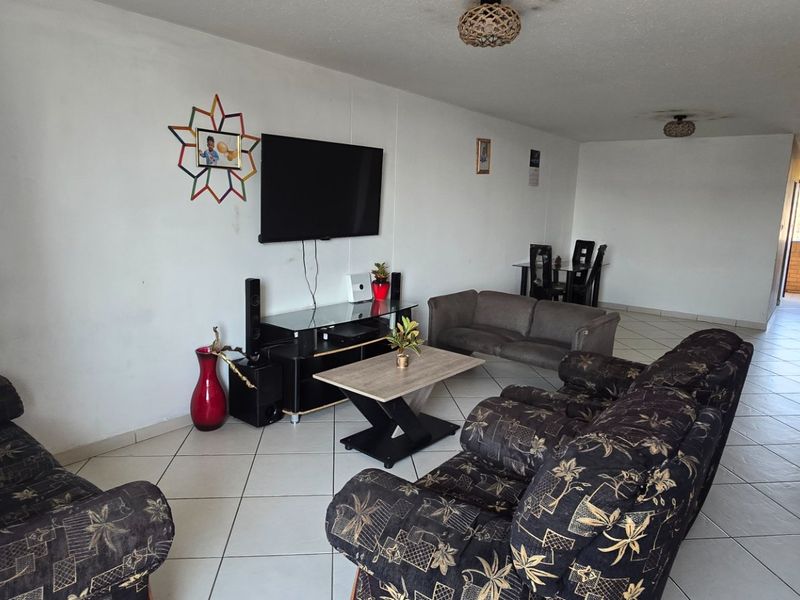 Spacious open-plan living area featuring neutral tiled flooring and direct access to an outdoor balcony space.