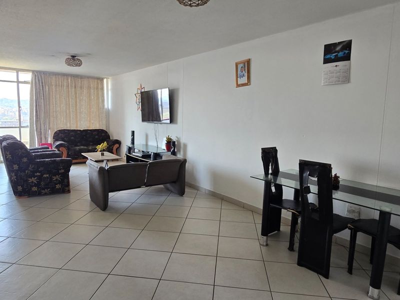 Spacious open-plan living and dining area featuring neutral tiled flooring and large sliding glass doors providing natural light.