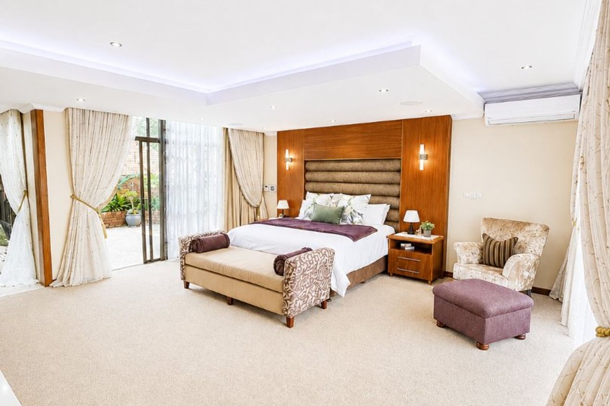 Spacious master bedroom featuring recessed ceiling lighting, cove lighting, a built-in headboard, and direct access to the outdoor area through sliding glass doors.