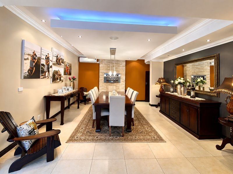 Spacious dining room featuring tiled floors, a stone feature wall with a built-in fireplace, recessed ceiling lighting, and decorative crown molding.