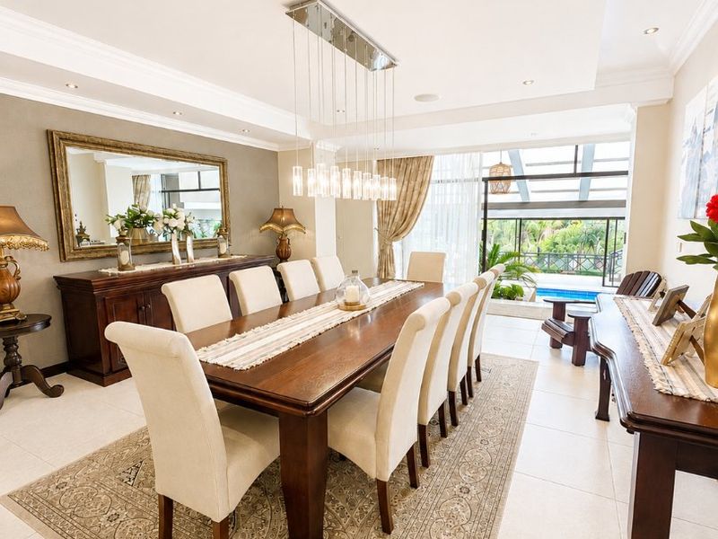 Elegant dining room featuring tiled floors, crown molding, recessed lighting, and large sliding glass doors providing a view of the outdoor pool area.