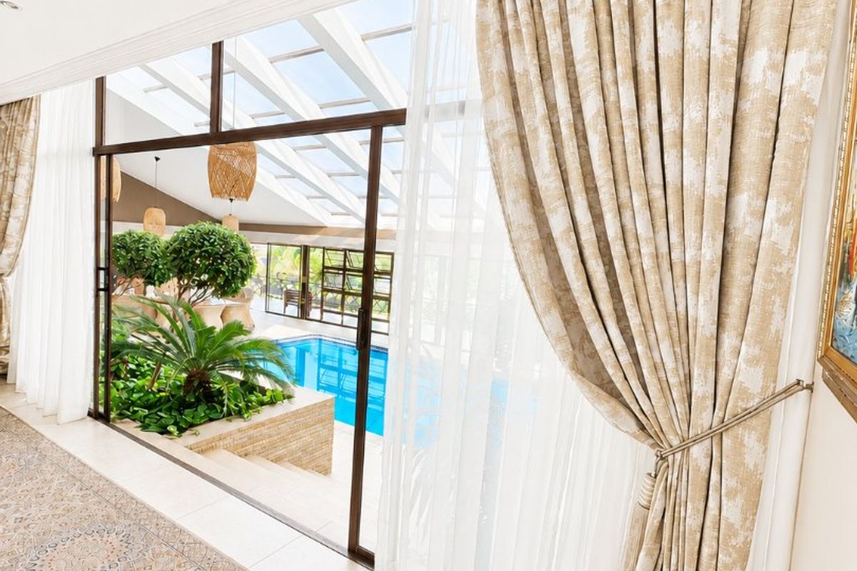 Bright living area featuring large sliding glass doors that open to an indoor pool area with a skylight and elegant crown molding.