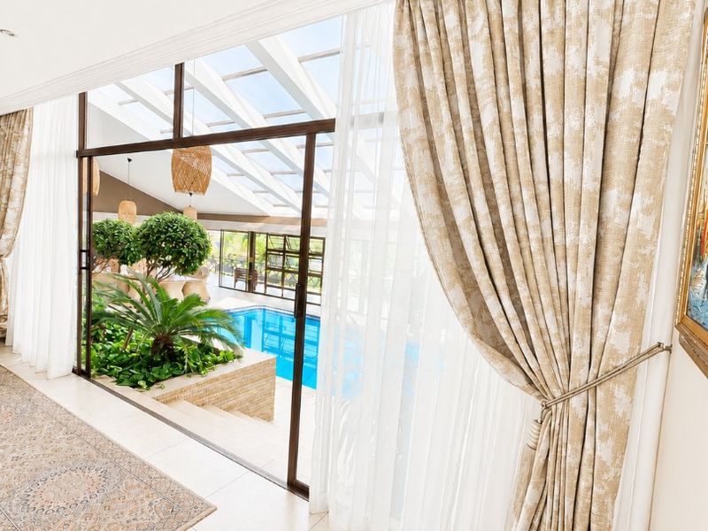 Bright living area featuring large sliding glass doors that open to an indoor pool area with a skylight and elegant crown molding.