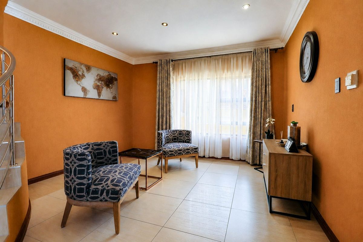 A bright living room featuring tiled flooring, crown molding, recessed lighting, and a spiral staircase, offering a comfortable and well-maintained living space.