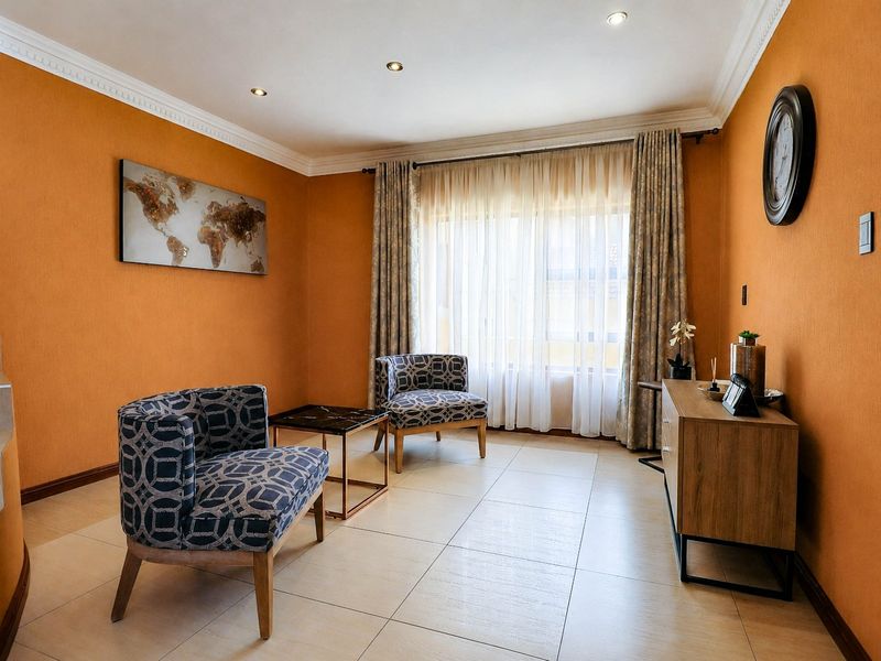 A bright living room featuring tiled flooring, crown molding, recessed lighting, and a spiral staircase, offering a comfortable and well-maintained living space.