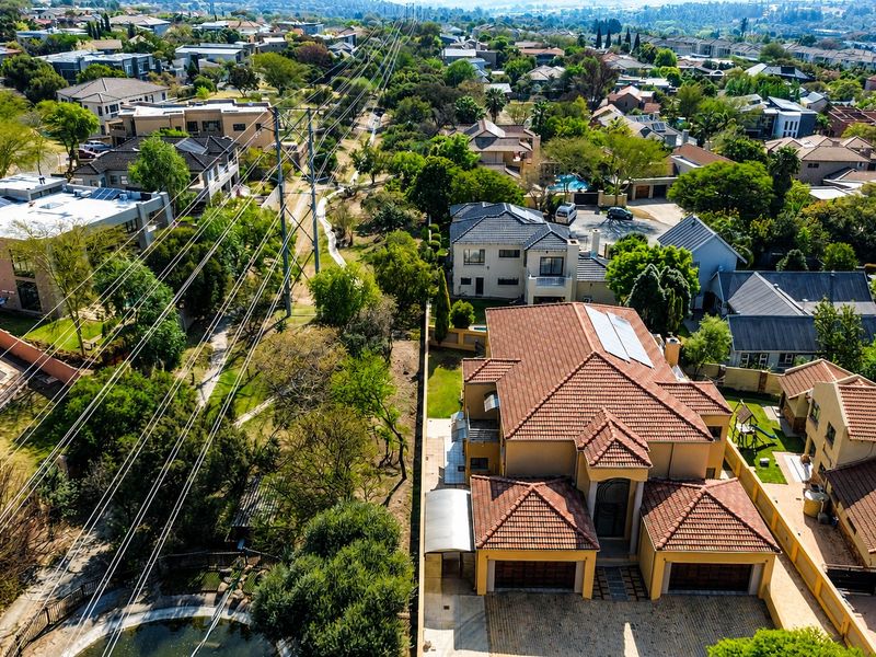 Aerial view of a residential property featuring a tiled roof with solar panels, a double garage, and a paved driveway within a suburban estate.