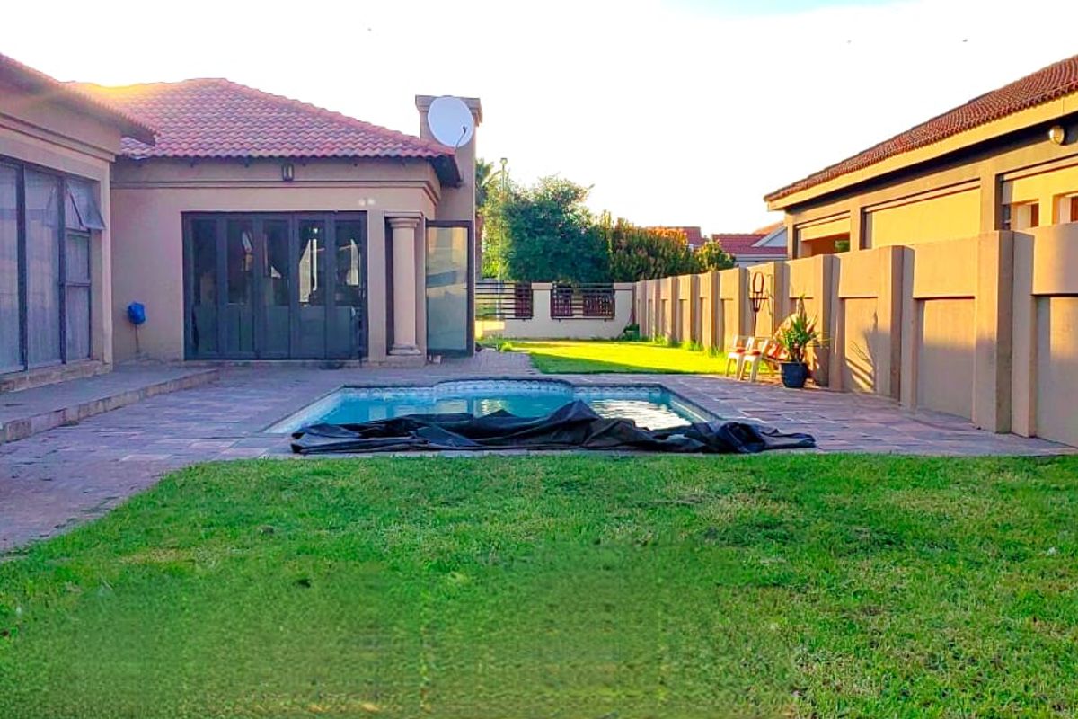Rear exterior view featuring a swimming pool, paved patio area, and surrounding boundary walls, providing a private outdoor space.