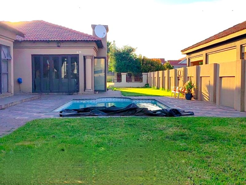 Rear exterior view featuring a swimming pool, paved patio area, and surrounding boundary walls, providing a private outdoor space.