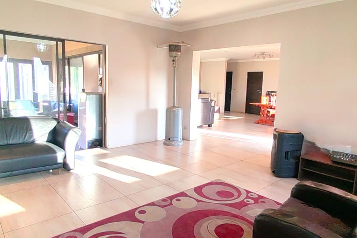 Spacious living area featuring large format floor tiles, neutral wall tones, and sliding glass doors providing access to the outdoor space.