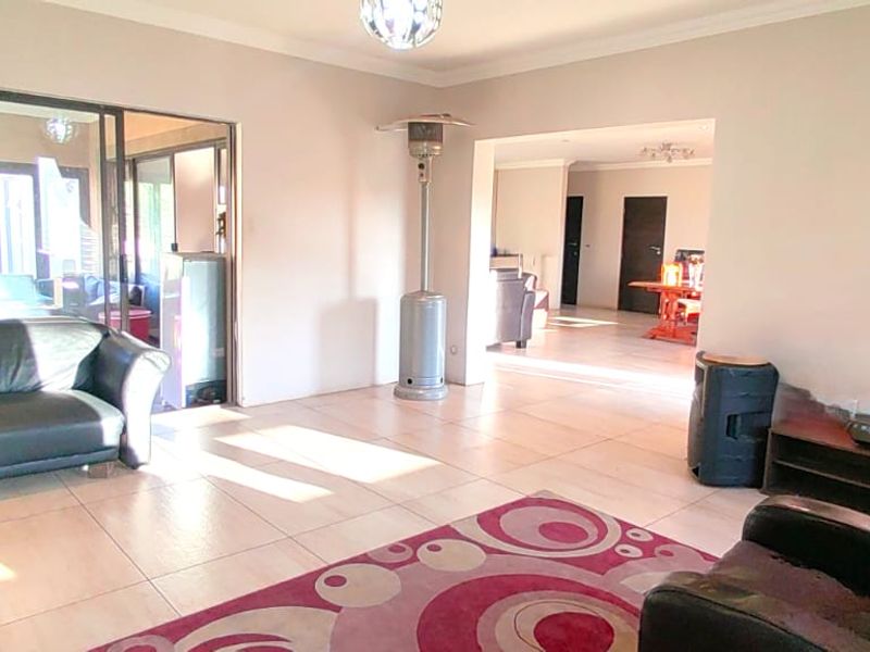 Spacious living area featuring large format floor tiles, neutral wall tones, and sliding glass doors providing access to the outdoor space.