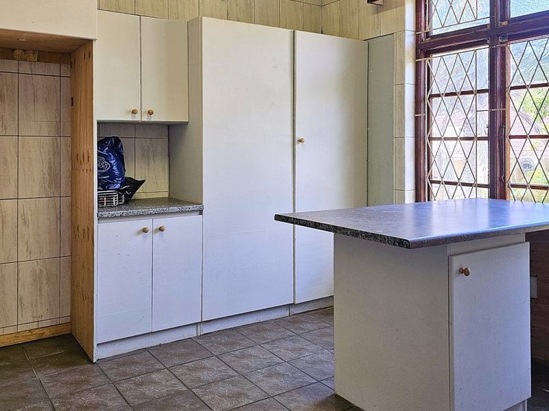 A dated kitchen featuring built-in cabinetry, laminate countertops, and tiled finishes, offering a blank canvas for a modern renovation.