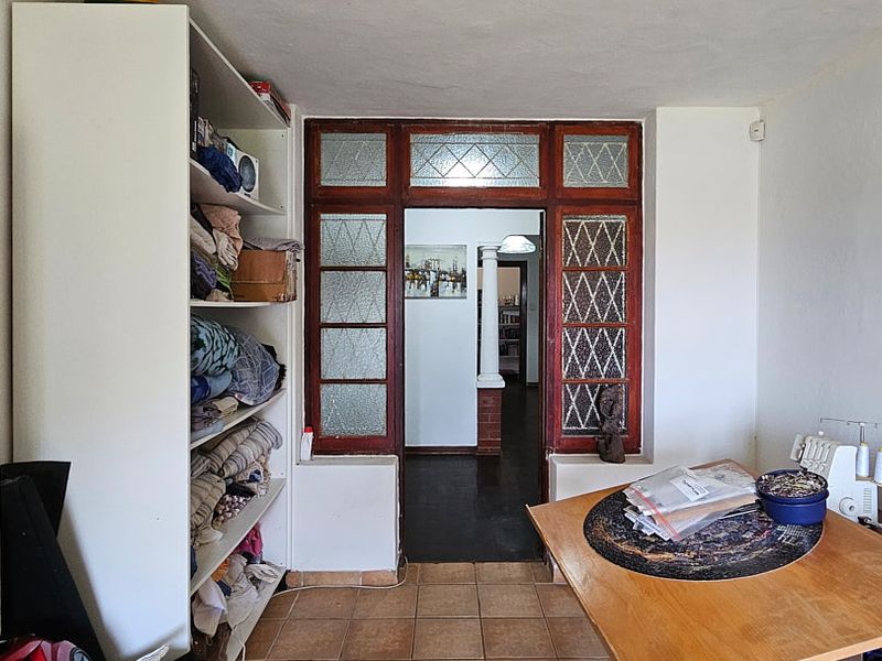 A living area featuring built-in shelving and a distinctive leaded glass doorway leading to an adjacent room, finished with tiled flooring.