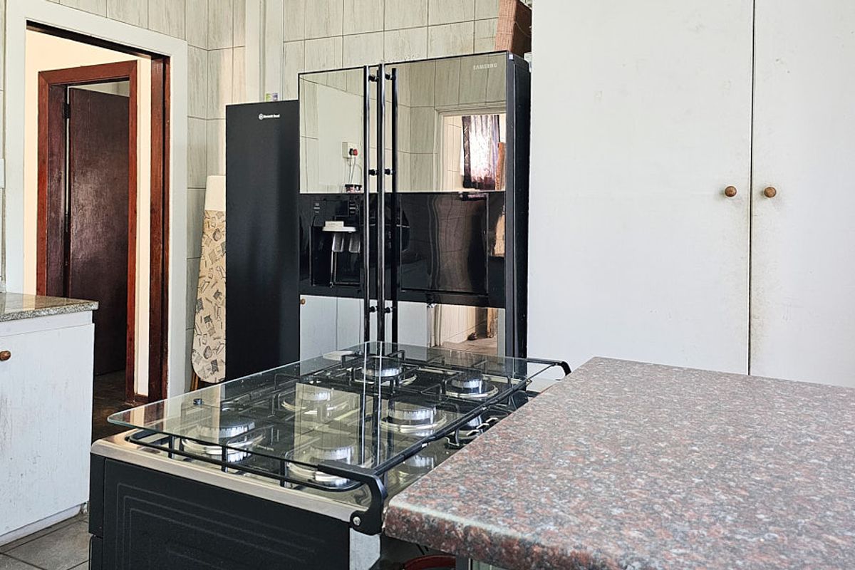 A functional kitchen featuring a gas cooktop, granite countertops, and built-in cabinetry with tiled wall finishes.