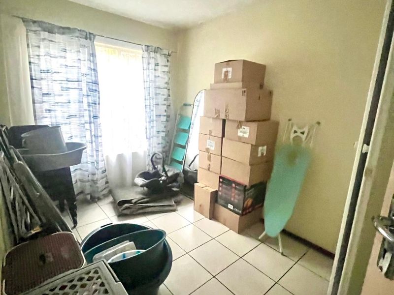 A small utility room featuring tiled flooring and a window, currently used for storage.