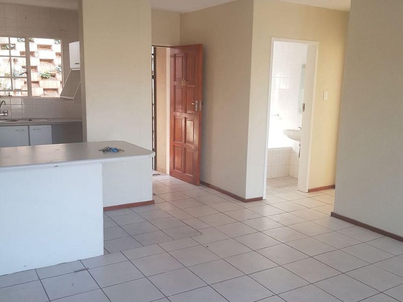 Open plan living area featuring tiled flooring, a functional kitchen with cabinetry, and access to an adjacent bathroom.