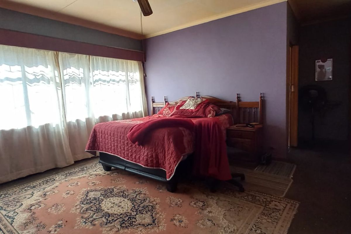Spacious bedroom featuring extensive built-in wooden cupboards, a ceiling fan, and large windows allowing for natural light.