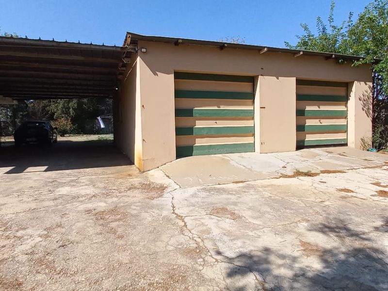 Exterior view of a double garage with an attached carport and a weathered concrete driveway.