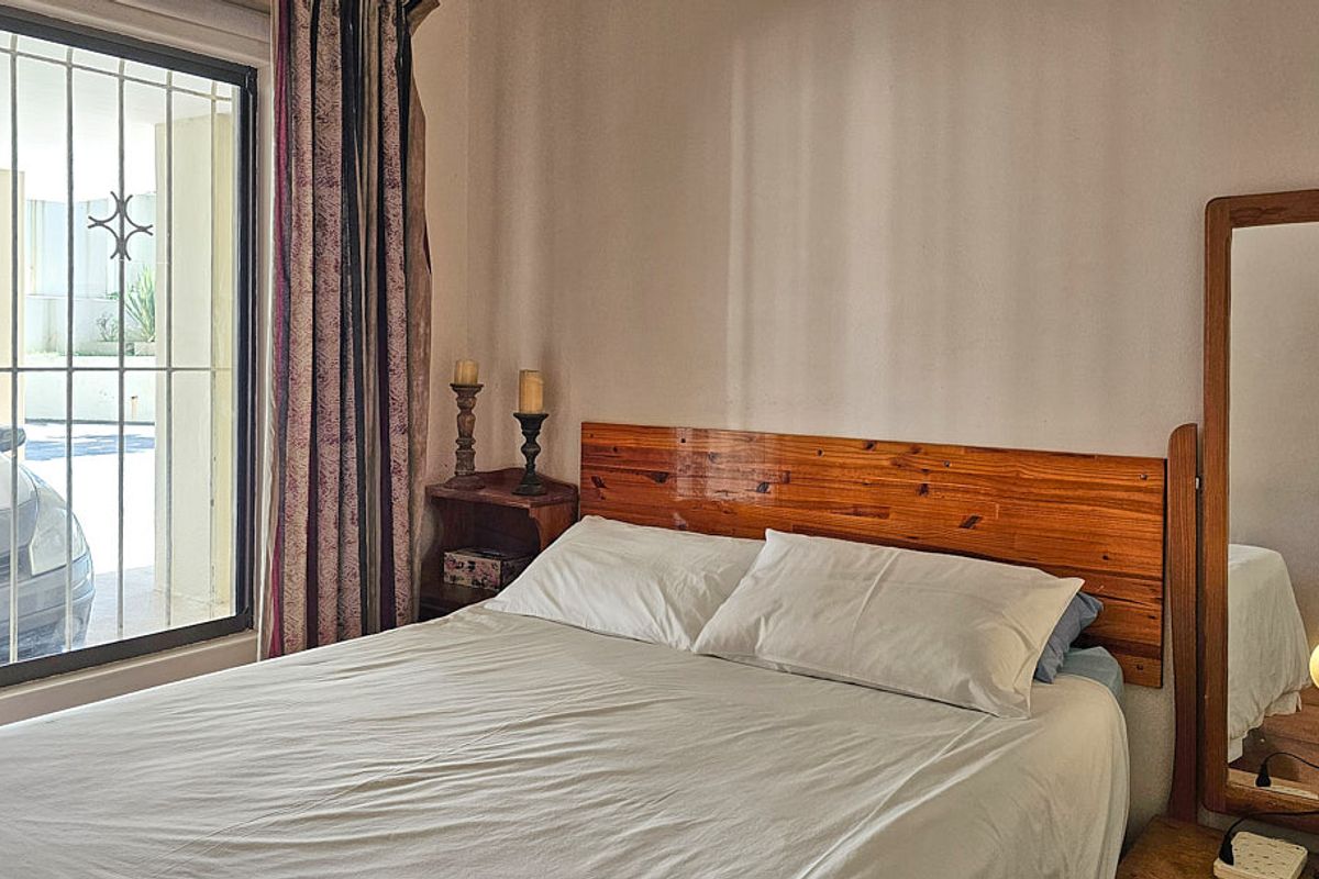 A bedroom featuring a sliding glass door with security bars, providing natural light and access to the exterior.