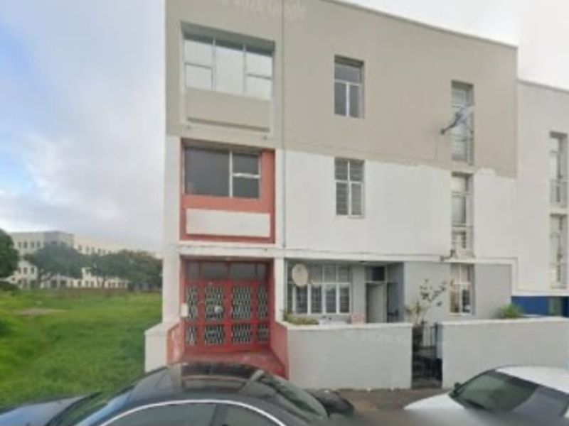Front elevation of a multi-story apartment building featuring a security gate, aluminium windows, and a boundary wall.