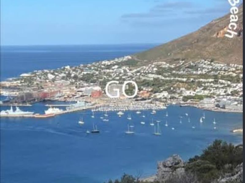 A scenic elevated coastal view overlooking the harbor, town, and surrounding mountains.