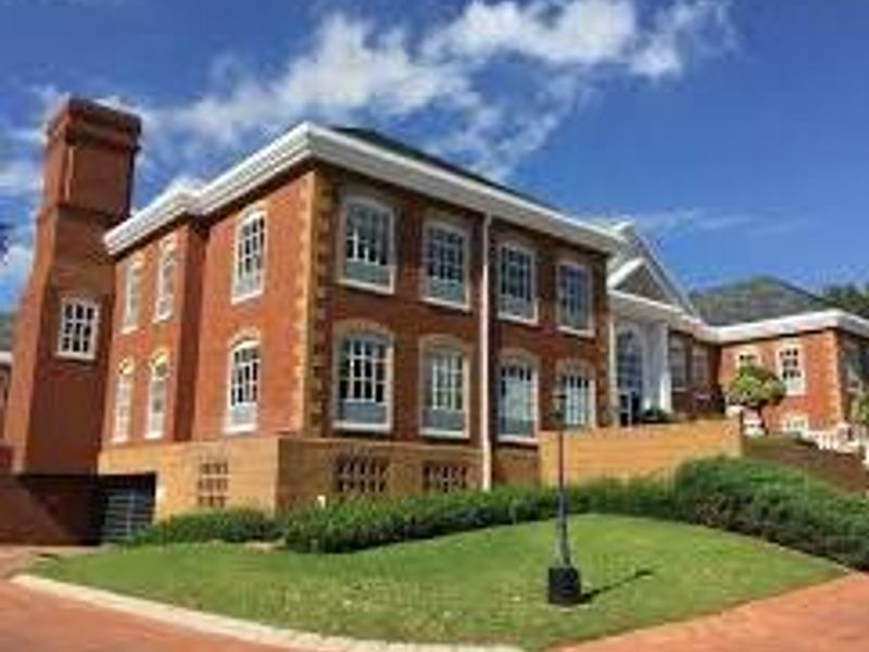 A well-maintained commercial building featuring a classic red brick facade, prominent chimney stack, and manicured lawn with paved driveway access.