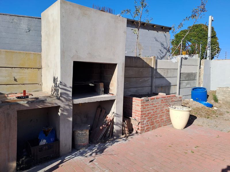 Outdoor entertainment area featuring a built-in braai, brick paving, and a perimeter boundary wall, currently in an unfinished state.