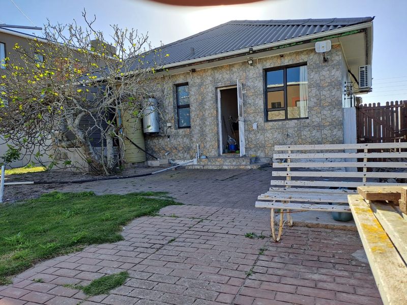 Rear exterior view of the property featuring stone cladding, a paved patio area, and an external geyser installation.