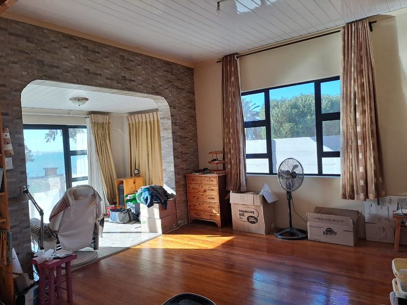Spacious living area featuring polished timber flooring, a stone-clad feature wall, and large windows providing natural light and views.
