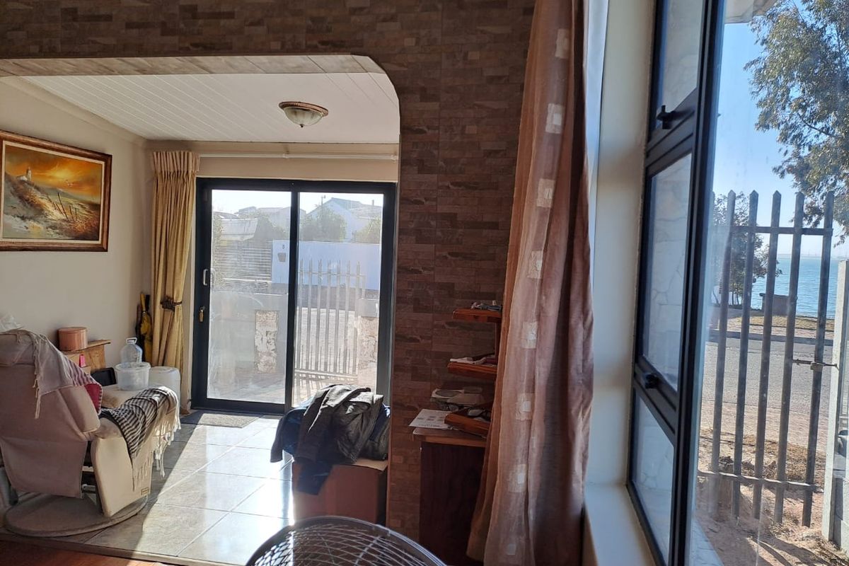 Living area featuring a mix of tiled and wooden flooring, textured wall accents, and large windows providing natural light and exterior views.