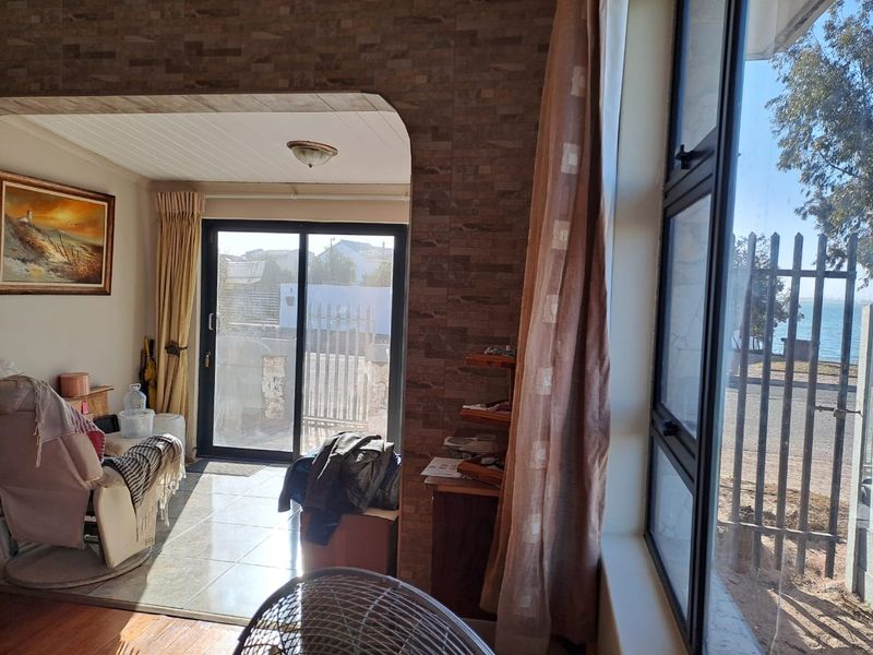 Living area featuring a mix of tiled and wooden flooring, textured wall accents, and large windows providing natural light and exterior views.