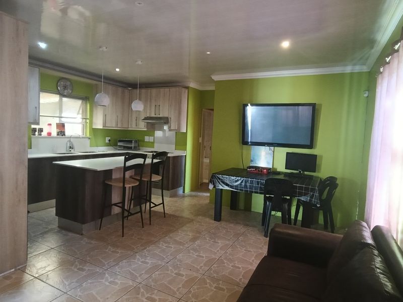 Open-plan living and kitchen area featuring modern cabinetry, a central island, tiled flooring, and bright green wall finishes.
