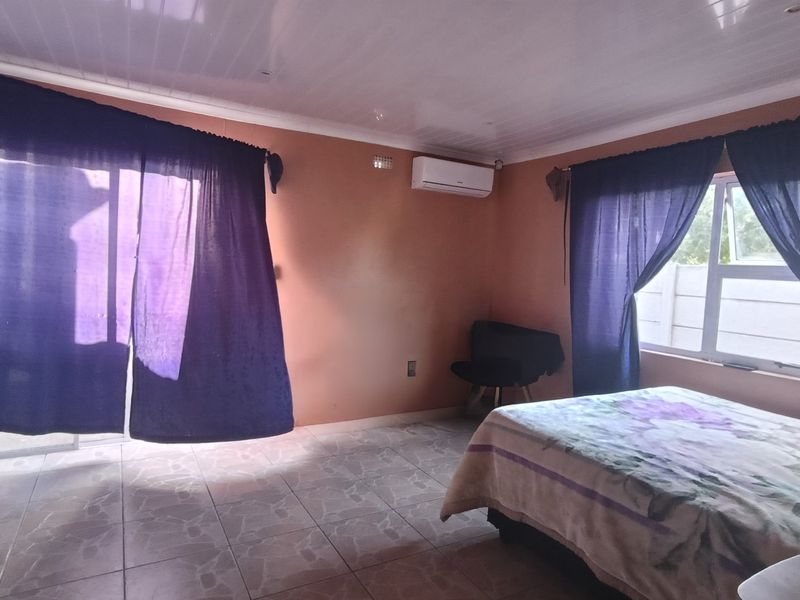 A bedroom featuring tiled flooring, an air conditioning unit, and access to the outdoors via a sliding glass door.