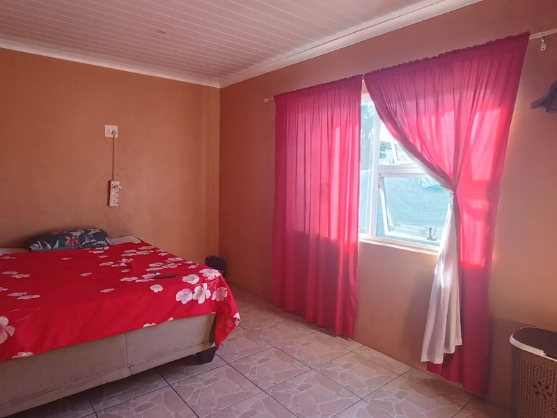 A bedroom featuring tiled flooring, a tongue and groove ceiling, and a sliding window with curtain fixtures.